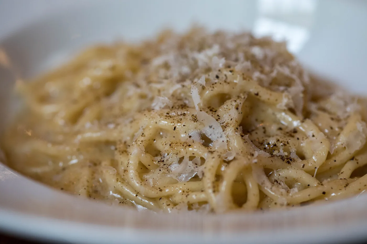 A bowl of cacio e pepe with black pepper and grated cheese