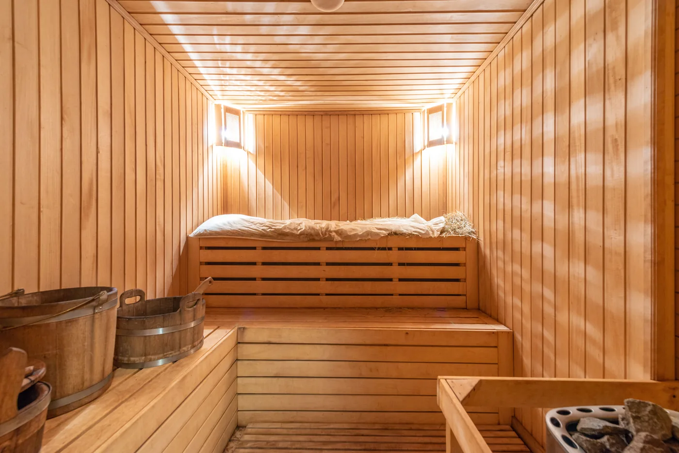 A hot wooden sauna with benches and water buckets