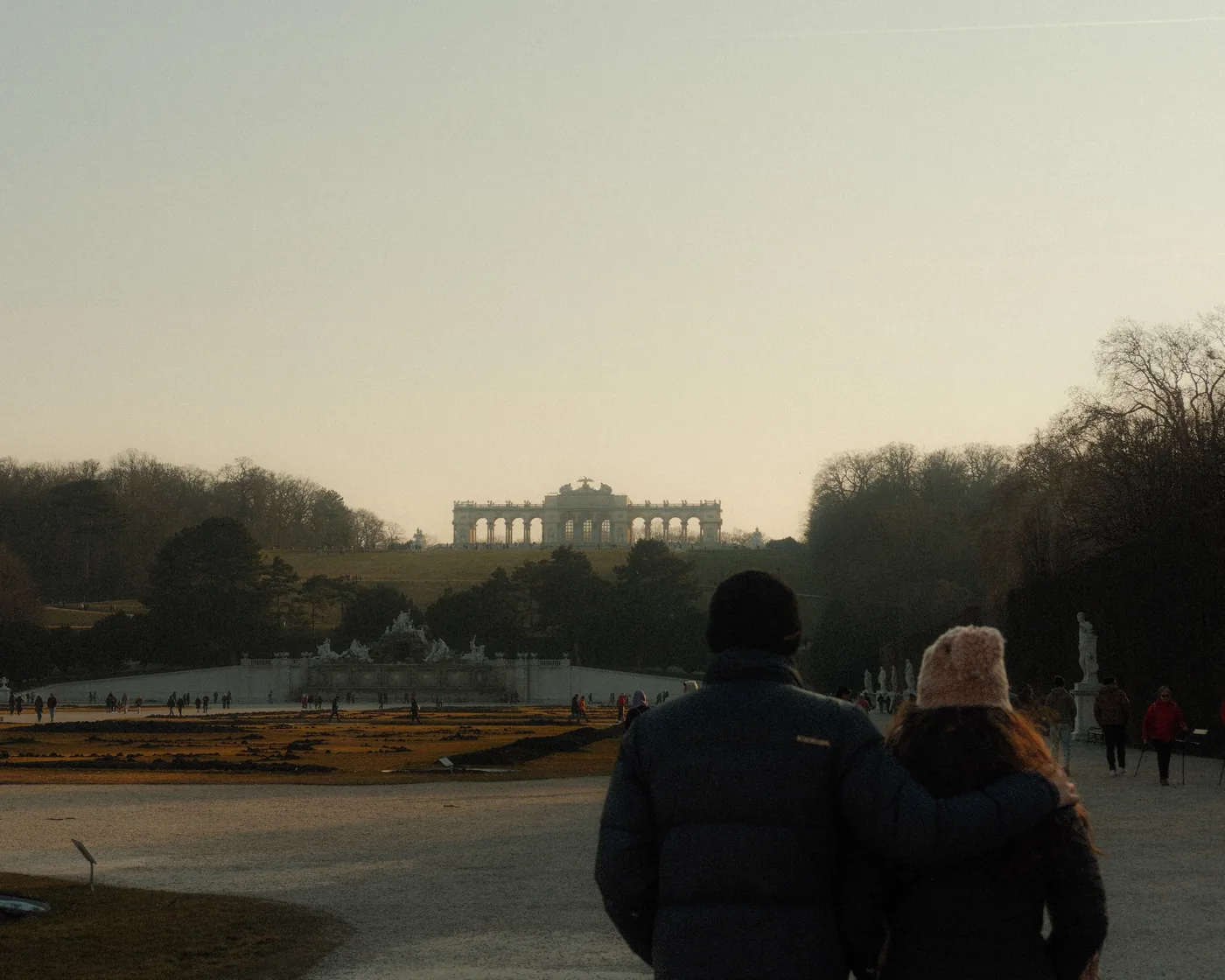 Two people looking across the bare winter gardens of Schönbrunn toward the Gloriette
