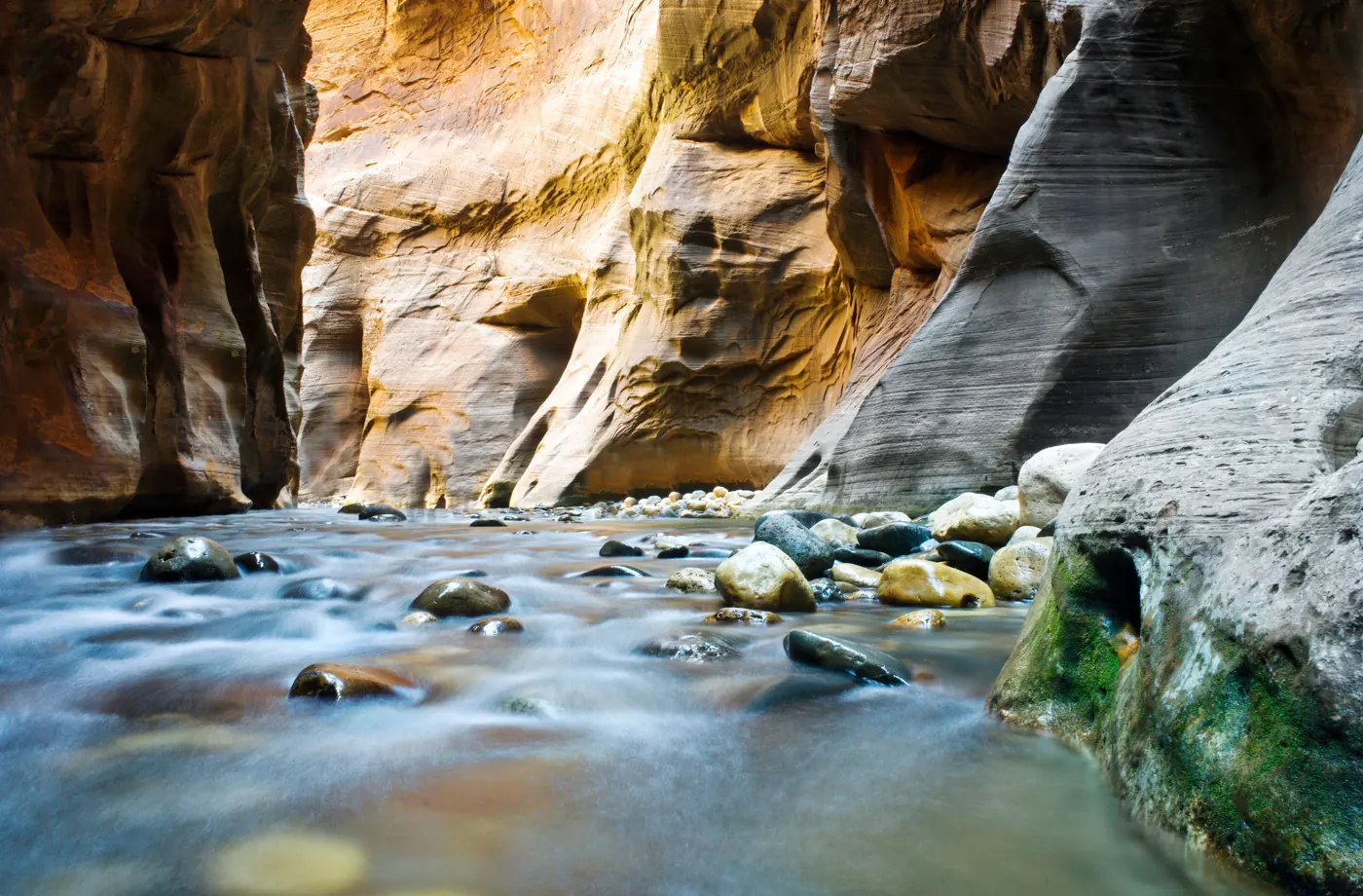 The Virgin River running between the striped canyon walls of the Narrows in Zion