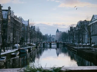 Snow on the gabled rooftops along an Amsterdam canal at dusk in winter
