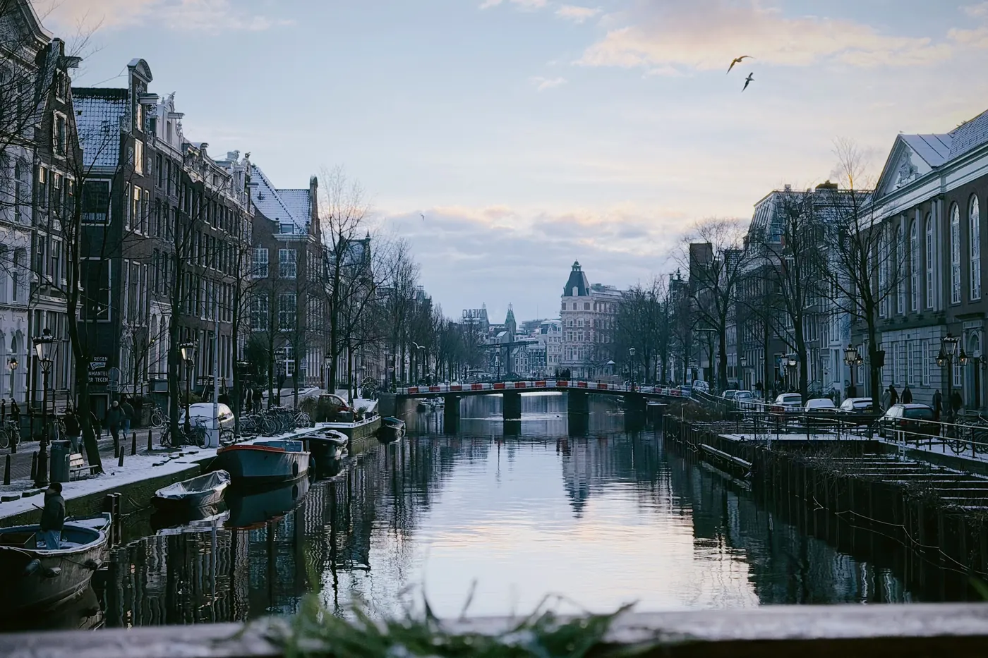 Snow on the gabled rooftops along an Amsterdam canal at dusk in winter