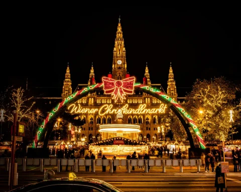 The illuminated Wiener Christkindlmarkt arch in front of Vienna's lit town hall at night