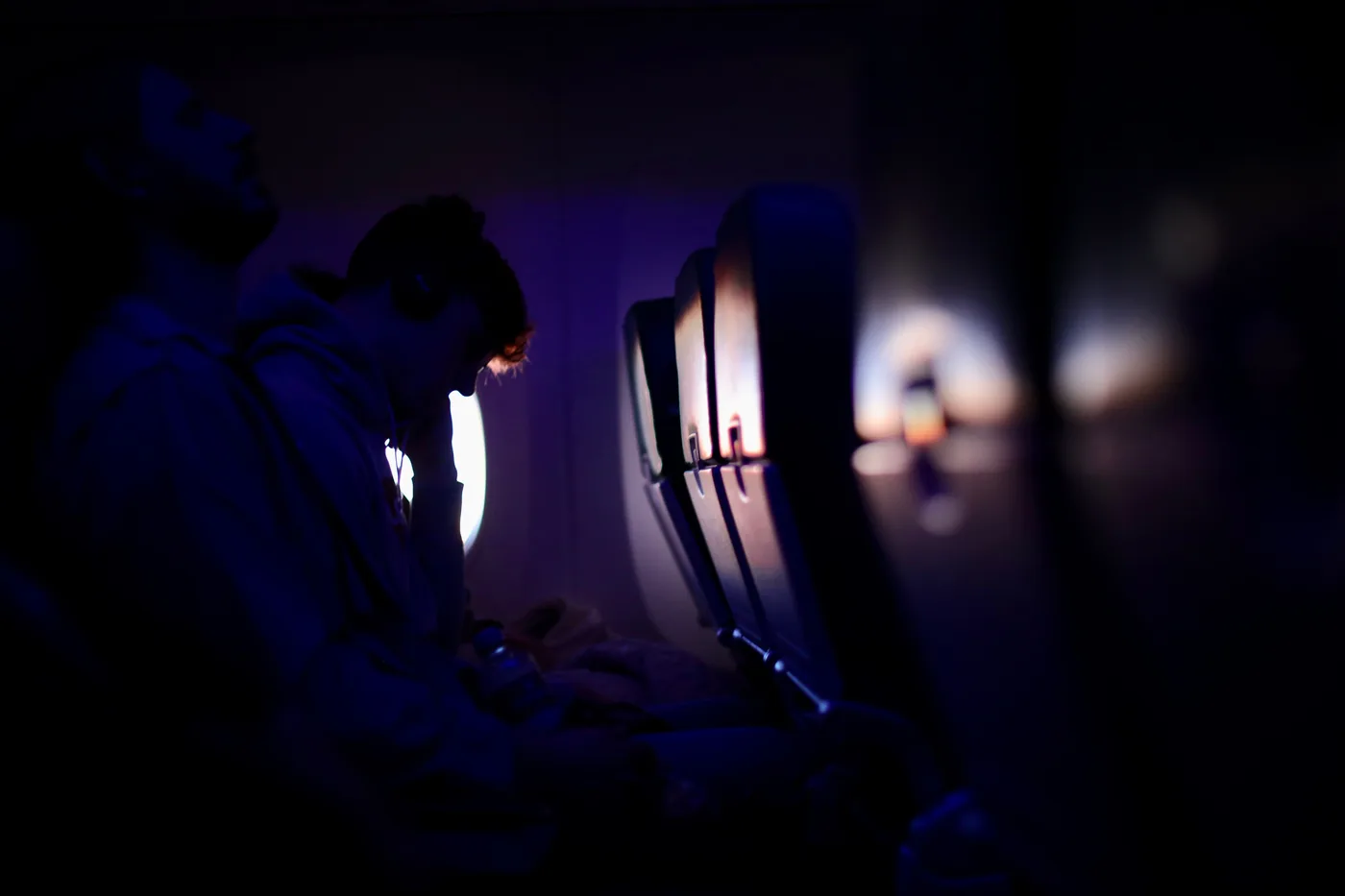 A dim airplane cabin lit blue during a night flight