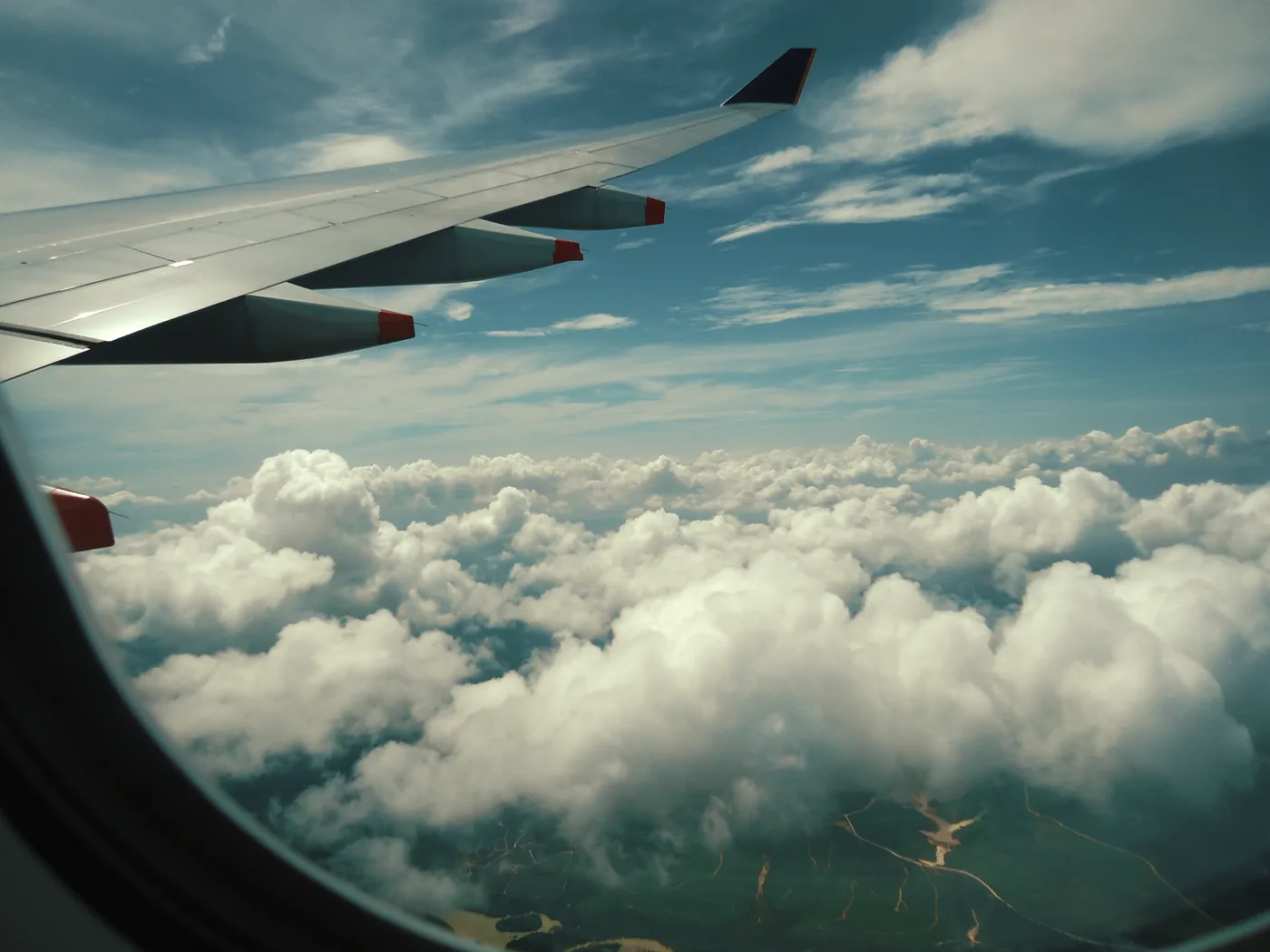 A wing and thick white clouds seen through an airplane window