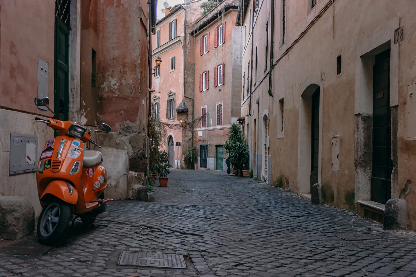 A cobbled lane in Trastevere with a scooter parked against the wall