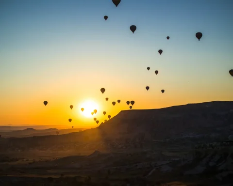 Hot air balloons rising over Cappadocia at sunrise