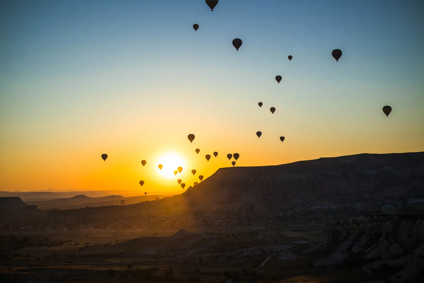 Hot air balloons rising over Cappadocia at sunrise