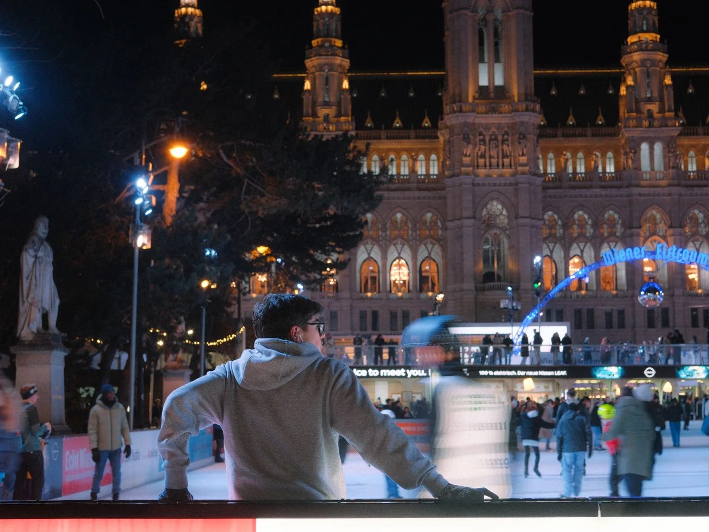 Skaters on the Wiener Eistraum rink at night with Vienna's town hall lit behind