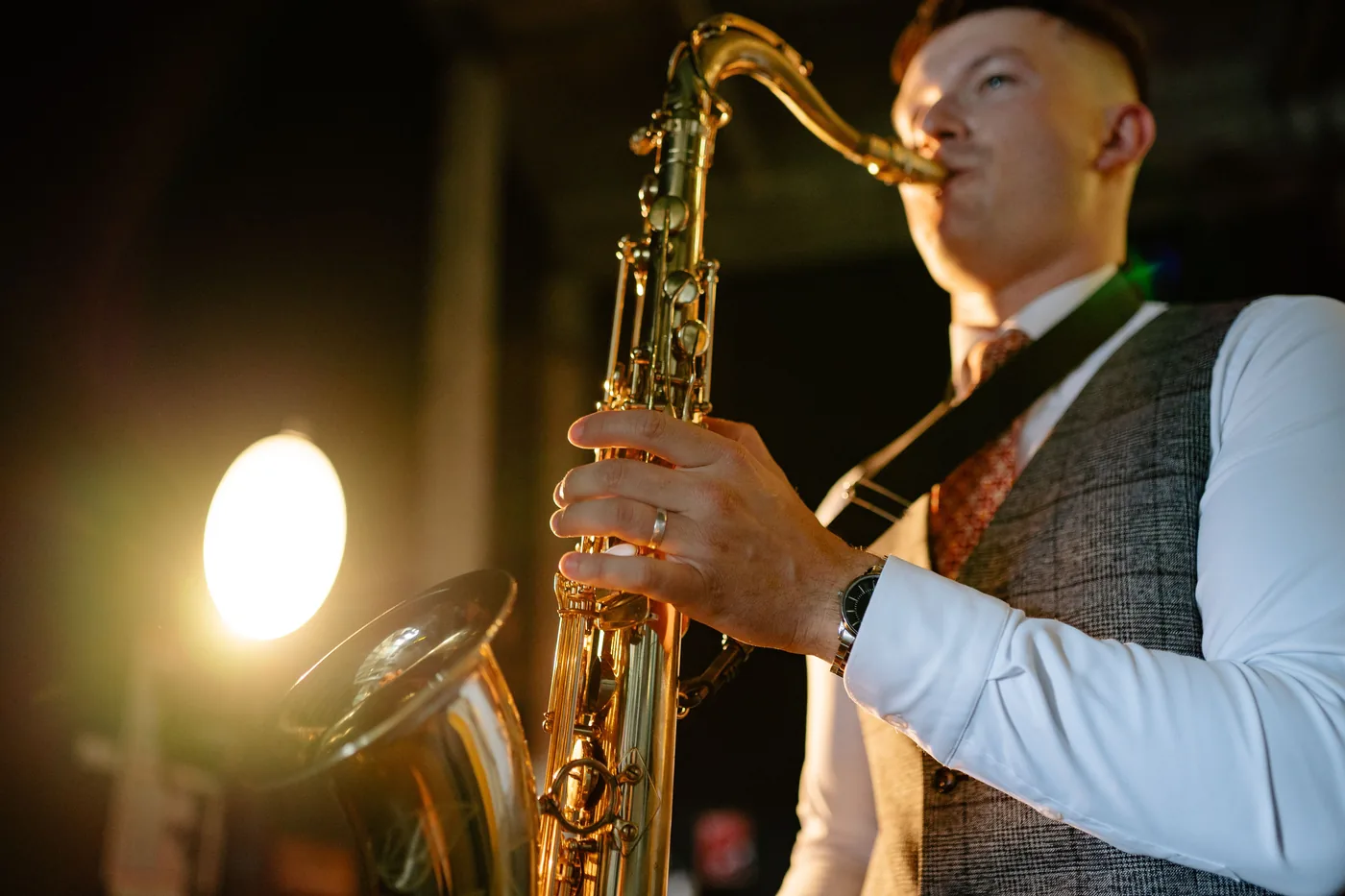 A saxophonist playing under a warm stage light