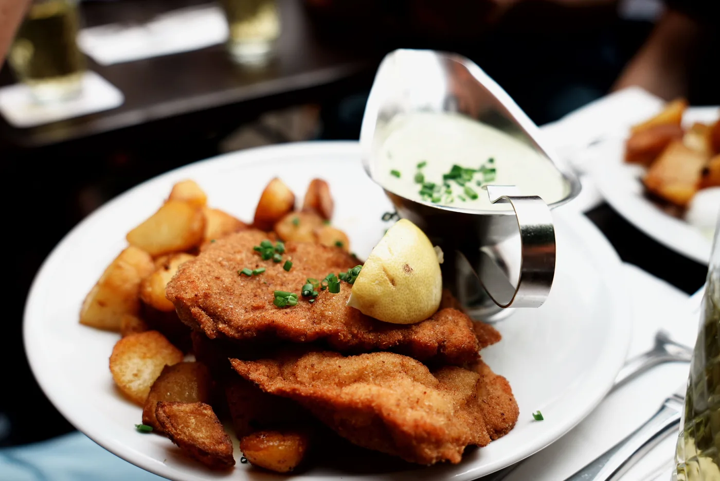 A large breaded schnitzel served with potatoes on a plate