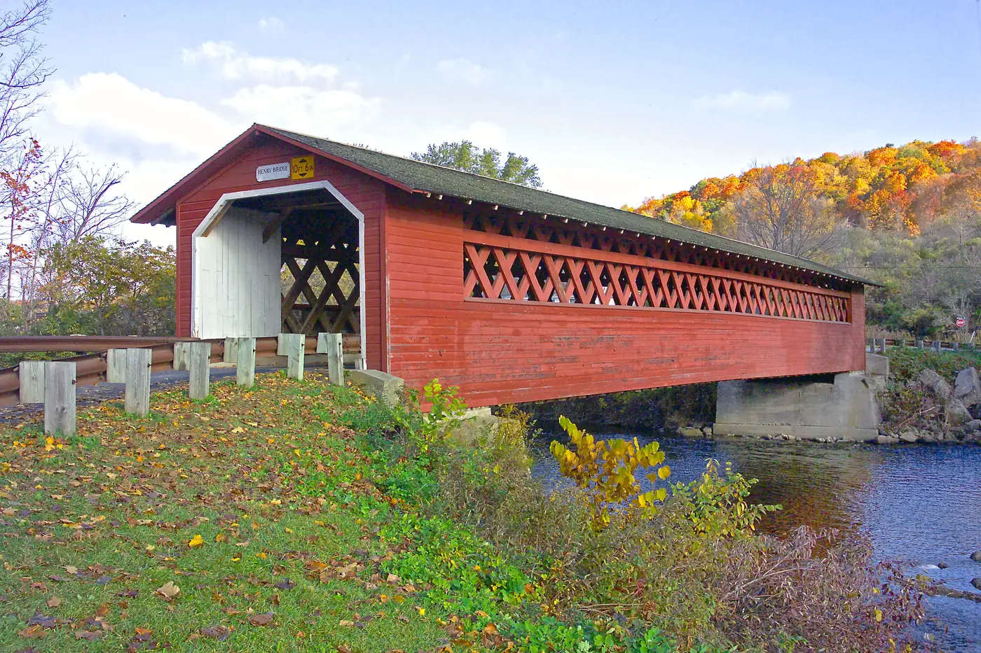 A red covered bridge over a river in Vermont in autumn