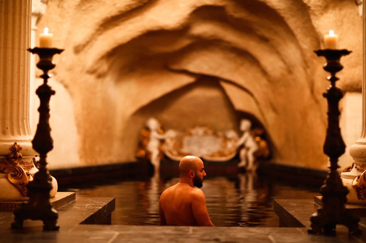 A candlelit indoor bath in a vaulted room