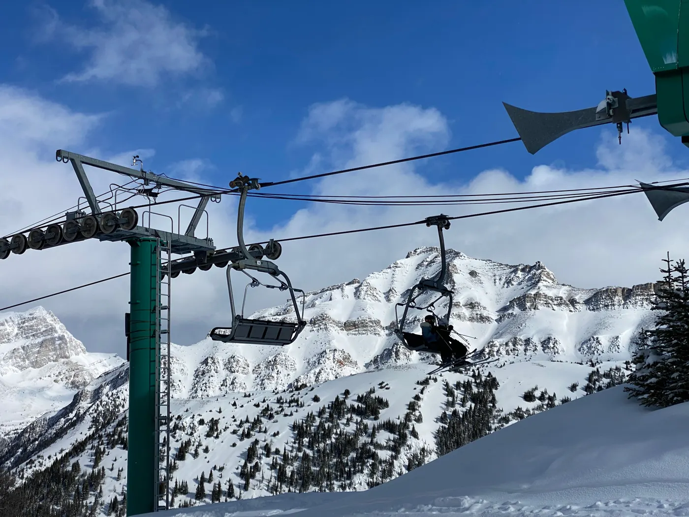 A chairlift climbing toward snowy peaks in the Canadian Rockies