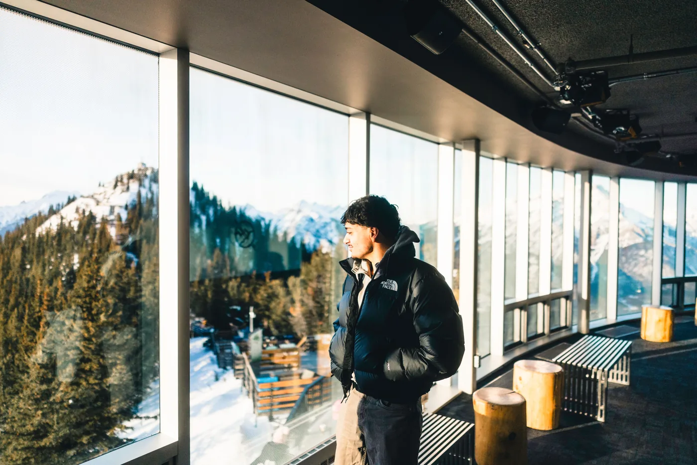 A visitor looking out at snowy peaks from the Banff Gondola summit building