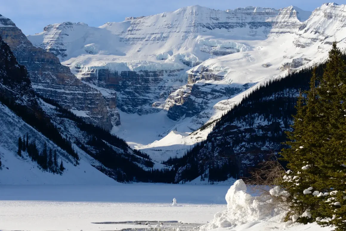 Frozen Lake Louise below snowy peaks and the Victoria Glacier in winter