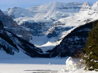 Frozen Lake Louise below snowy peaks and the Victoria Glacier in winter