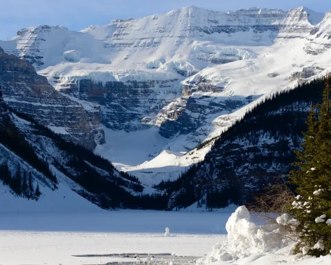 Frozen Lake Louise below snowy peaks and the Victoria Glacier in winter