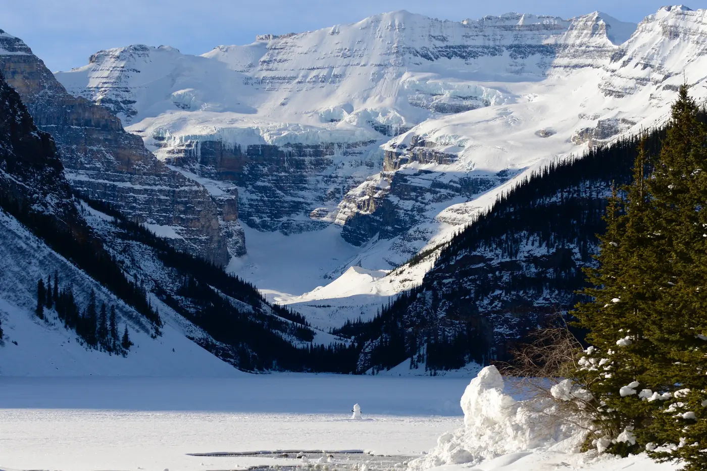 Frozen Lake Louise below snowy peaks and the Victoria Glacier in winter