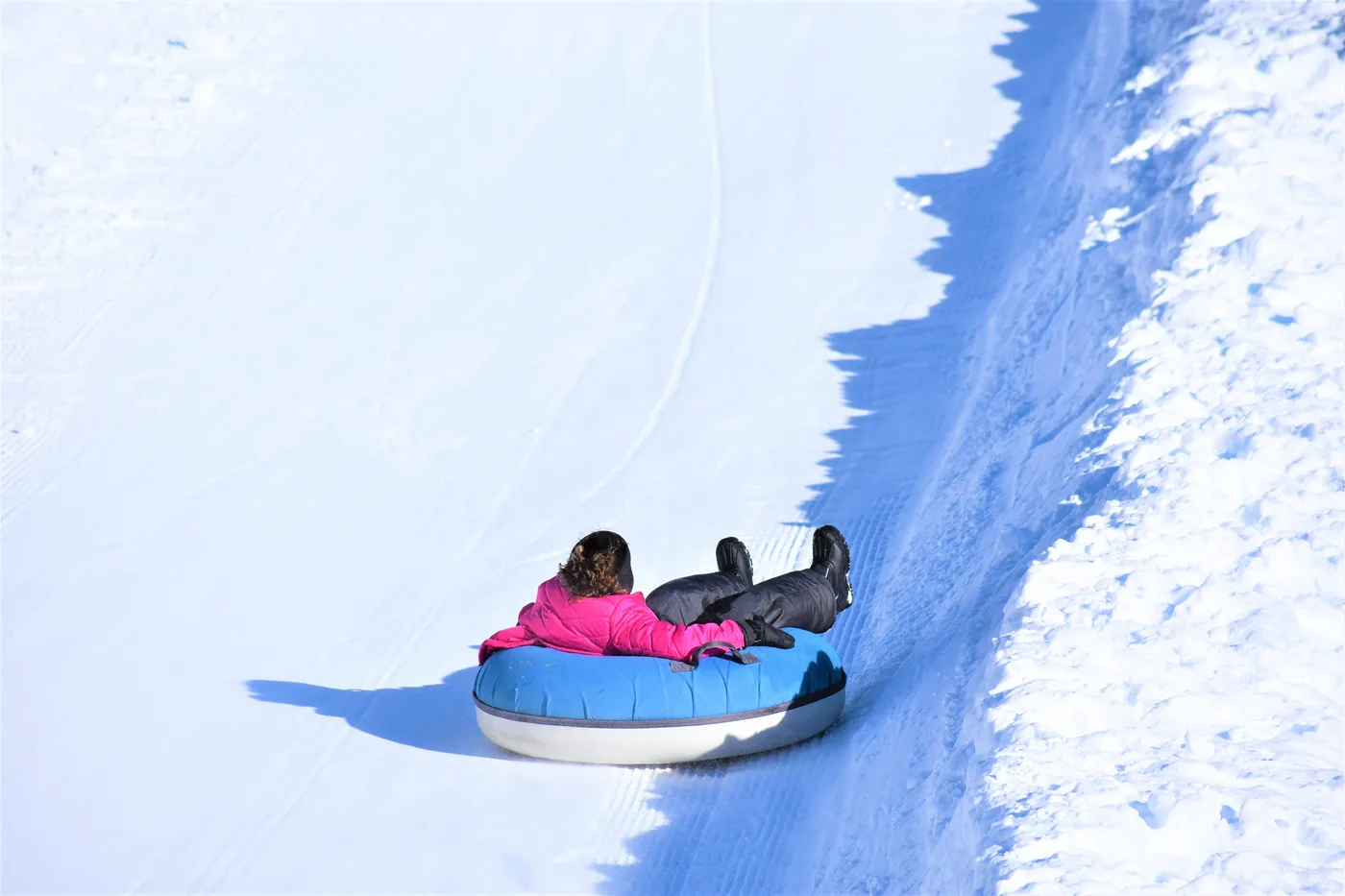 A person sliding down a snowy hill on an inner tube