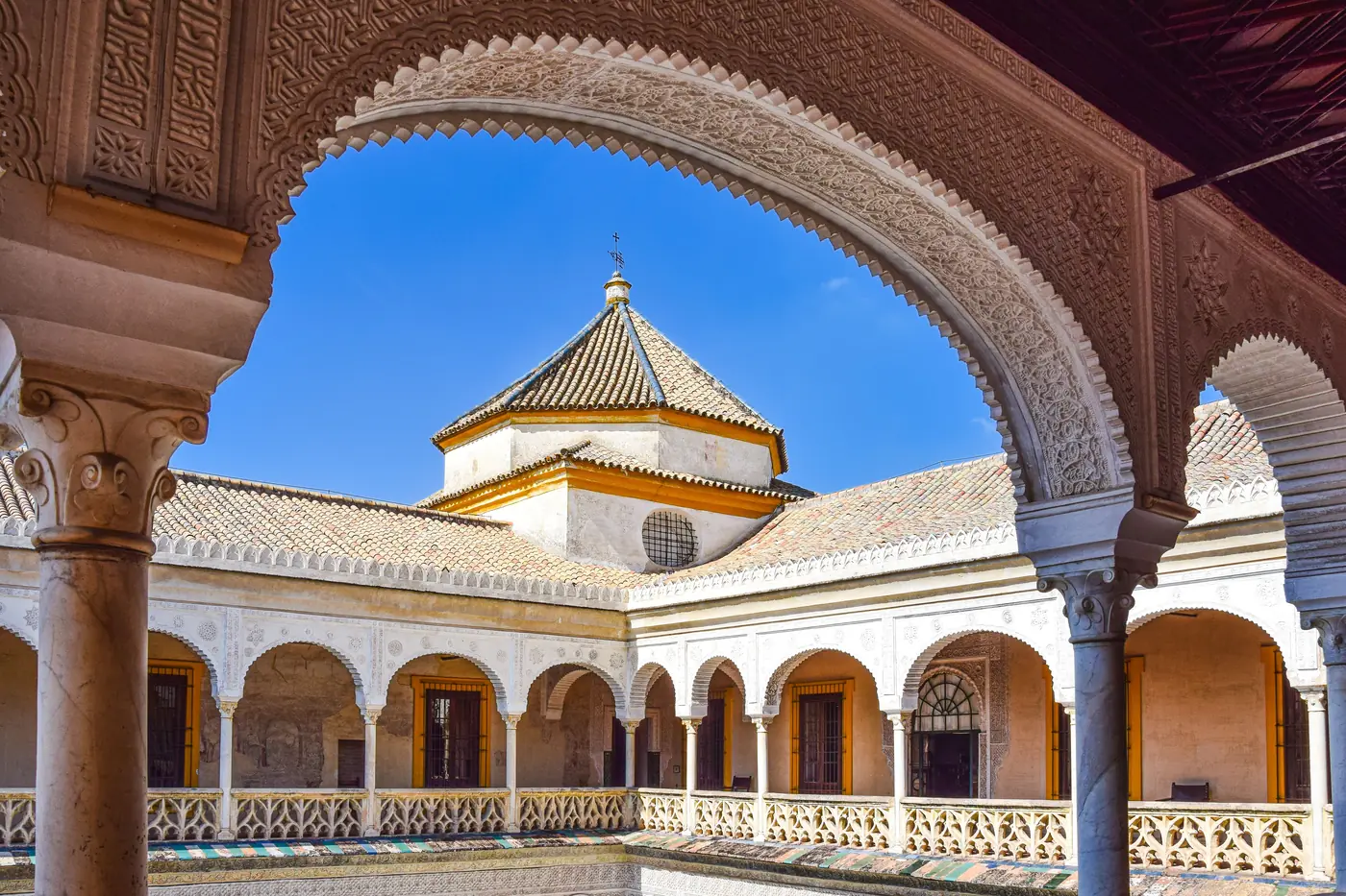 The main courtyard of Casa de Pilatos framed by a carved arch