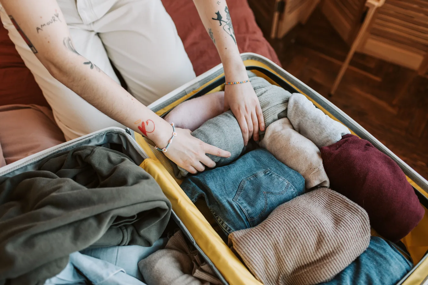Hands rolling clothes into an open suitcase