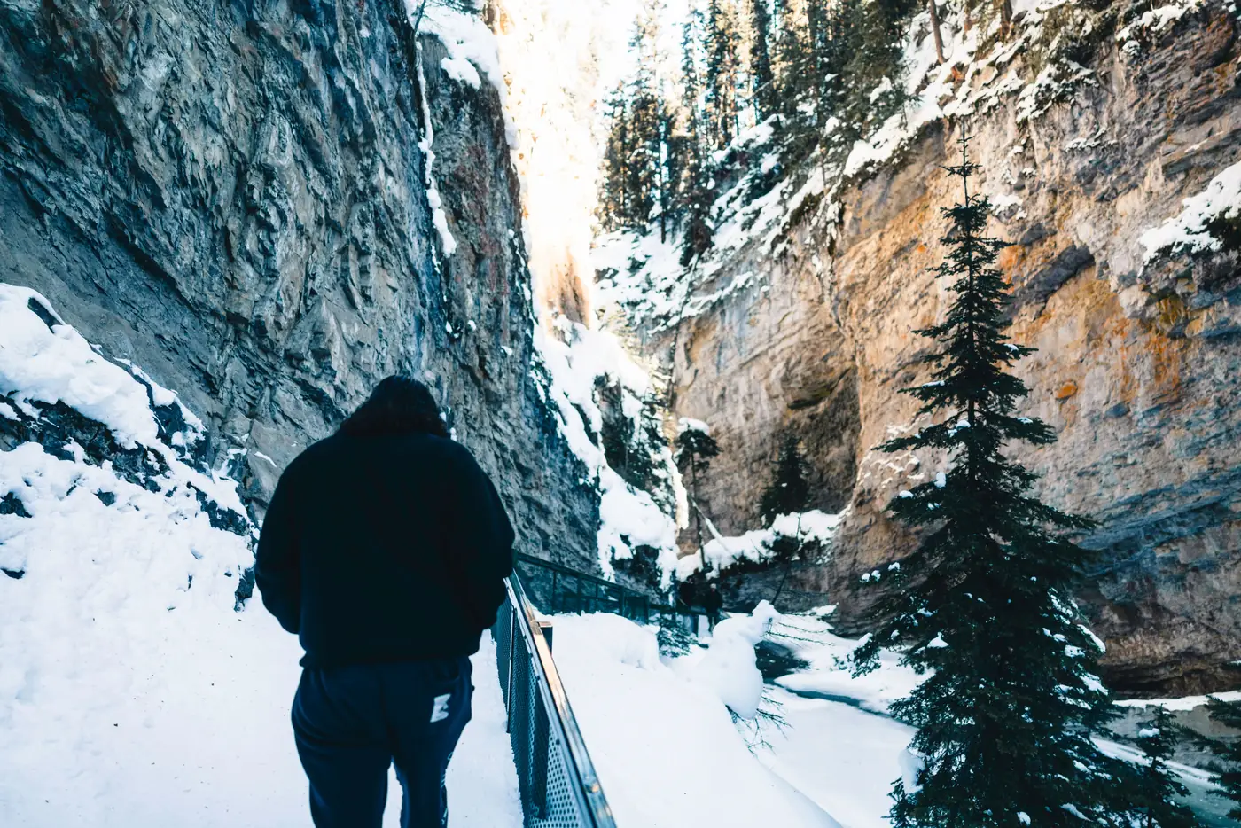 A hiker on the catwalk through snowy Johnston Canyon in Banff