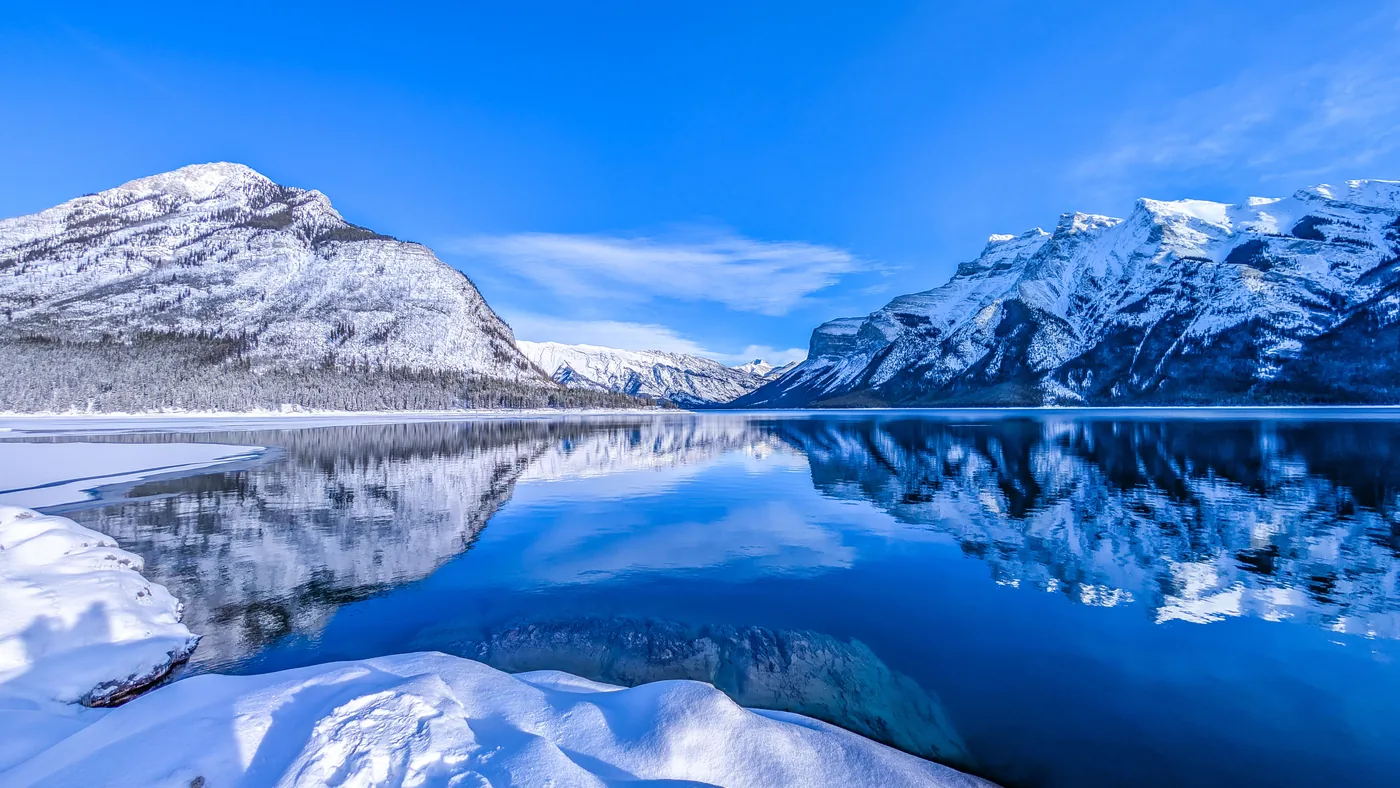 Snowy mountains reflected in Lake Minnewanka in winter