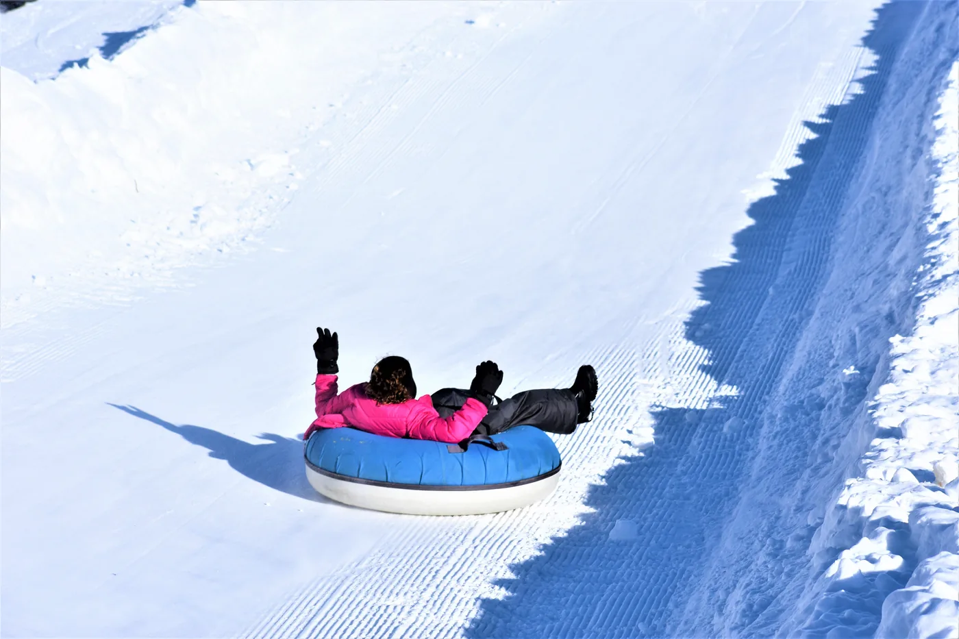 A person snow tubing down a groomed hill