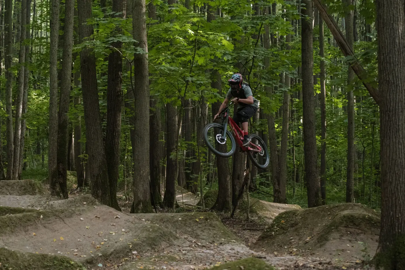 A mountain biker catching air on a forest trail
