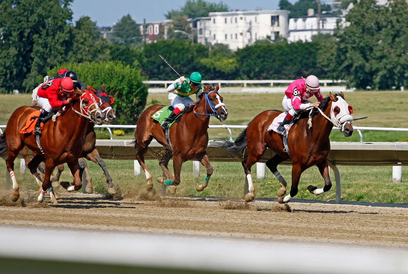 Jockeys racing thoroughbred horses down a dirt track
