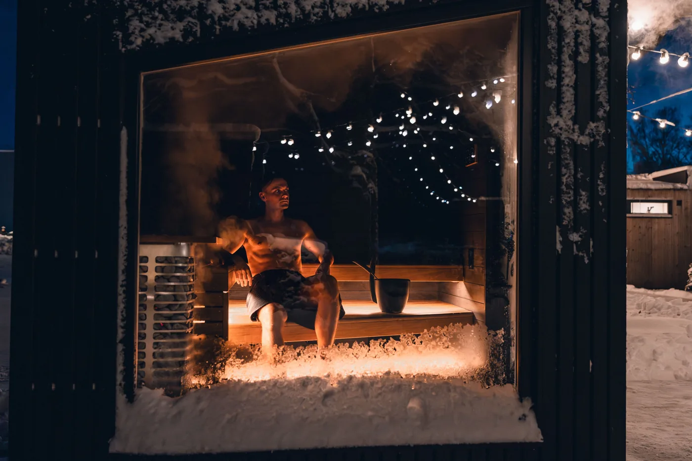 A warmly lit wooden sauna on a snowy winter evening