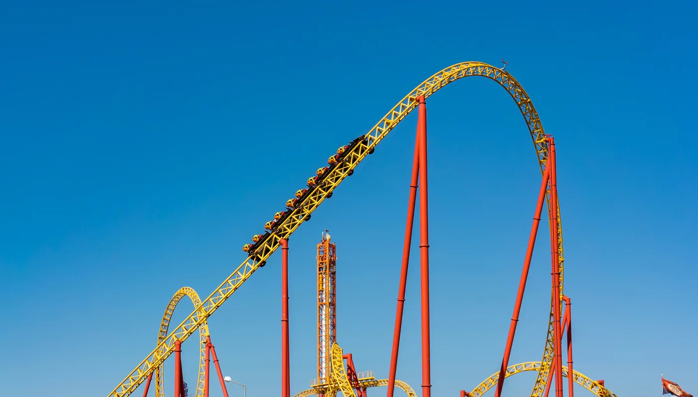 A yellow and red roller coaster against a blue sky