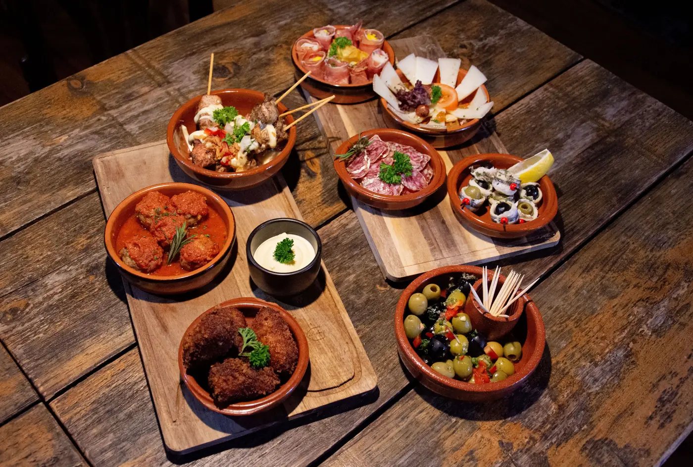 Plates of Spanish tapas on a wooden table