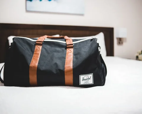 A weekender duffel bag sitting on a made hotel bed