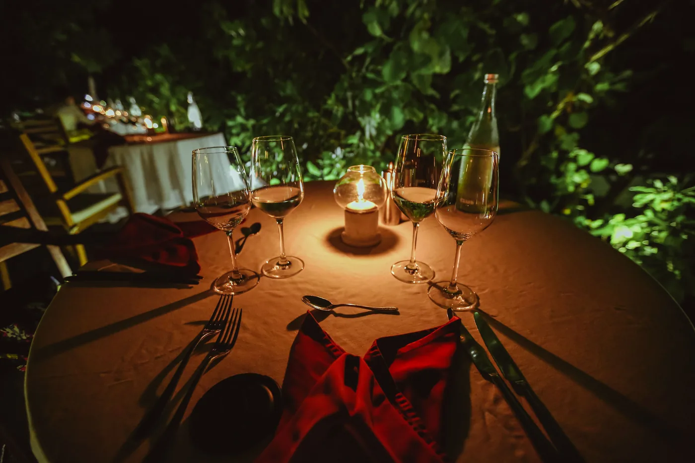 A candlelit restaurant table set for dinner outside at night