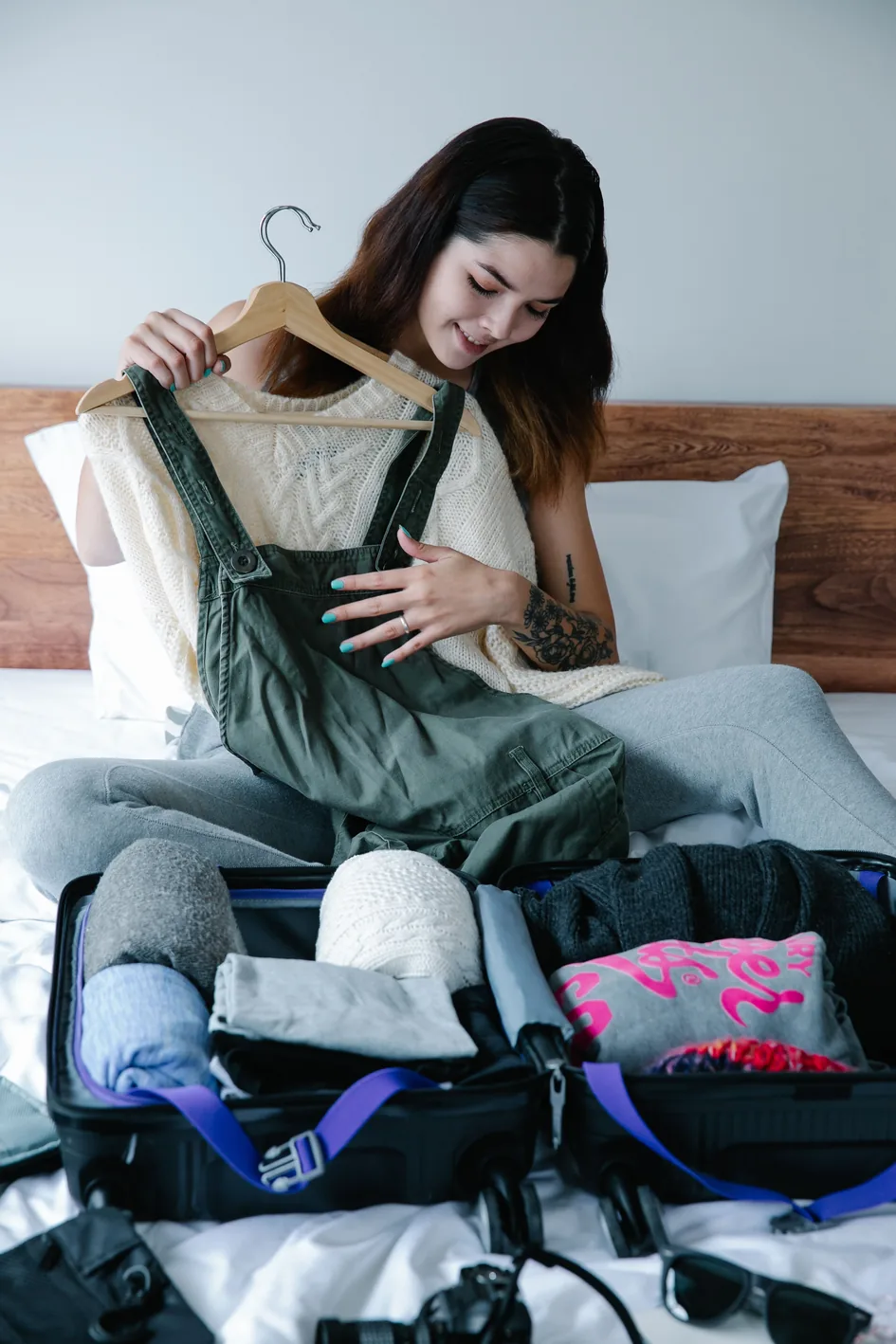 A traveler holding up an outfit on a hanger next to an open suitcase
